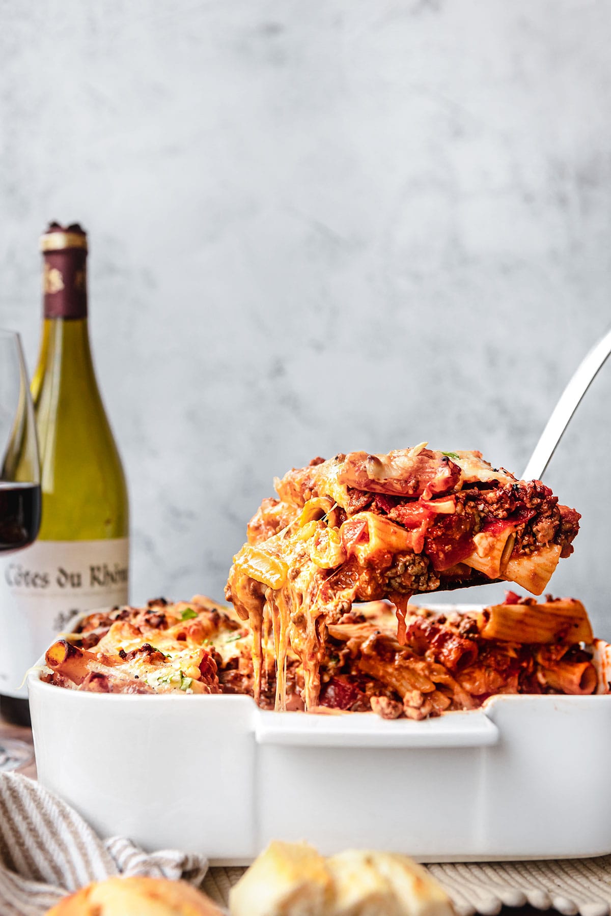 Cheesy Beef Pasta Bake in baking dish with spatula lifting piece out