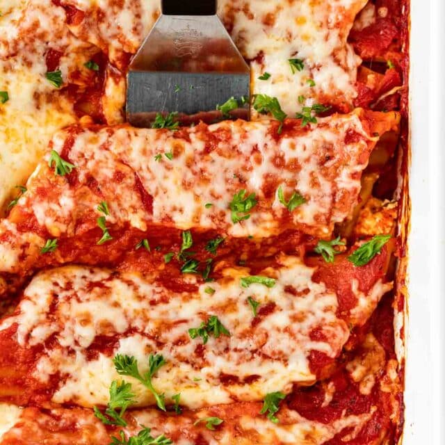 Cheesy Manicotti baked in pan with spatula