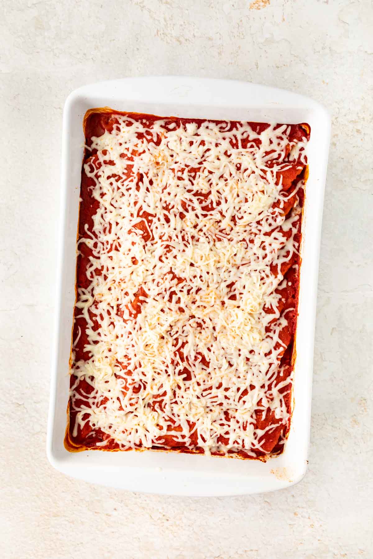 Cheesy Manicotti unbaked in pan with cheese