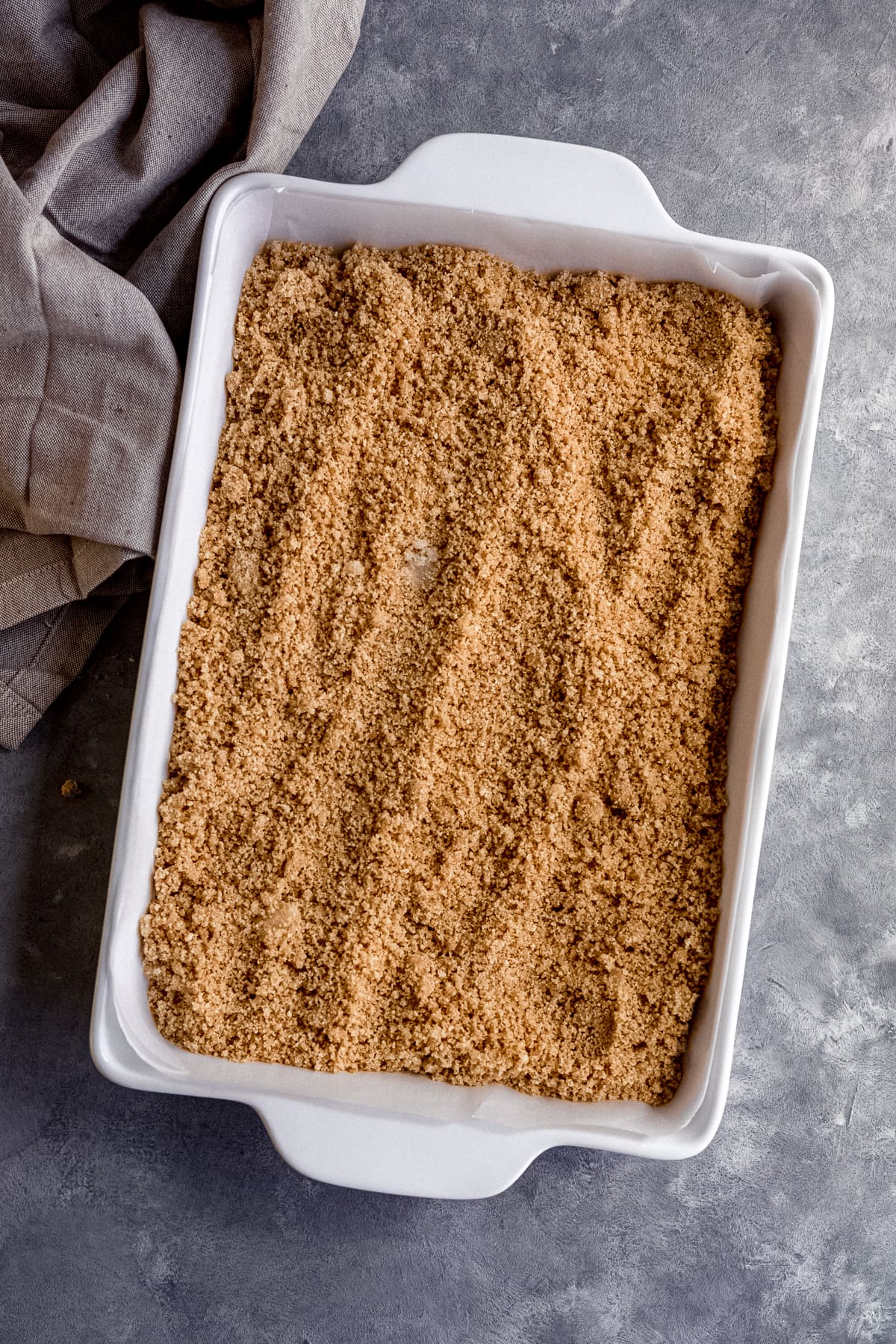 Graham cracker mixture for Chocolate Chip Cheesecake Bars in 9x13 baking dish