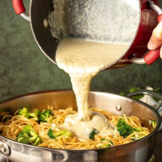 pouring finished sauce over pan of cooked pasta and broccoli. 4x3
