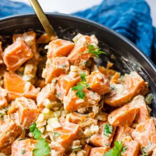 Creamy Spicy Sweet Potato Salad in serving bowl with spoon and cilantro garnish