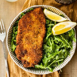 Crispy Breaded Chicken on plate with greens and lemons