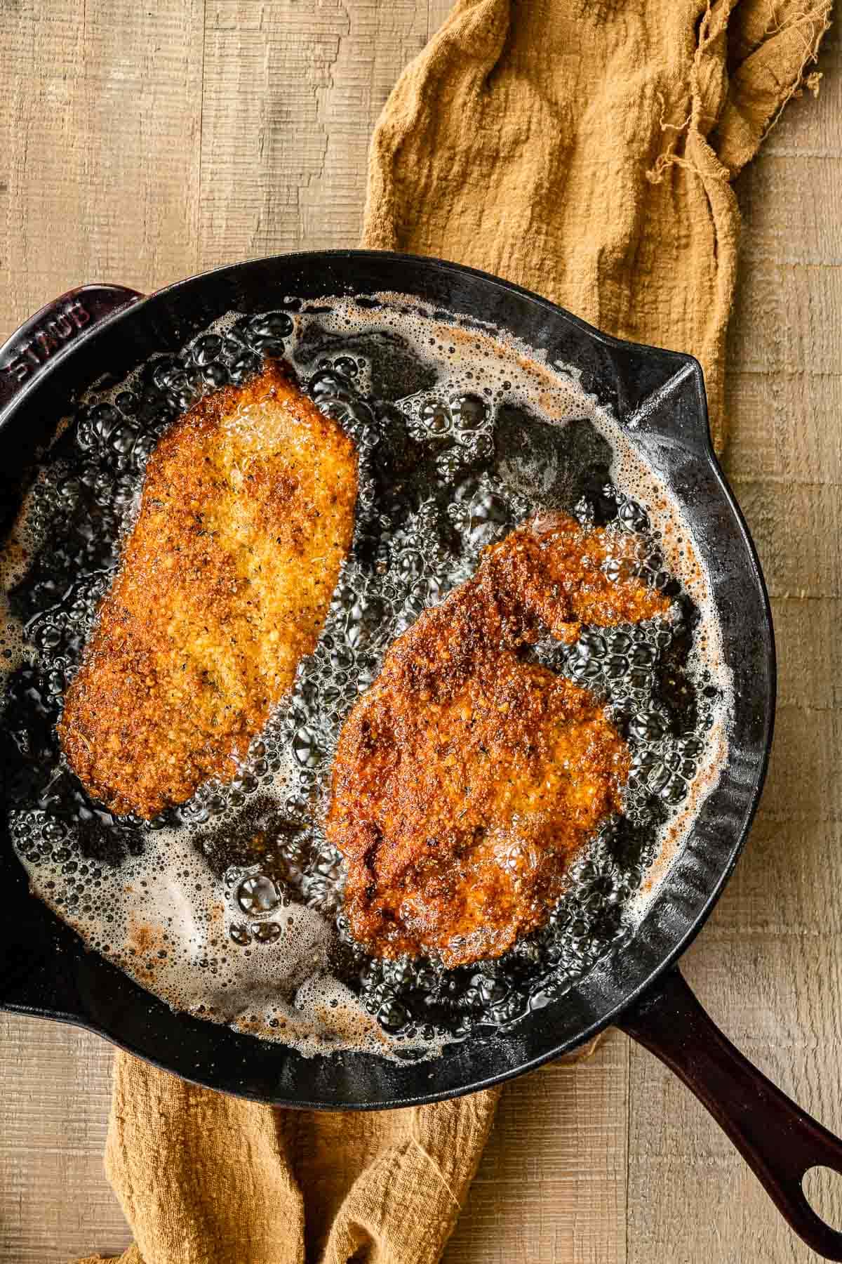 Crispy Breaded Chicken frying in cast iron pan