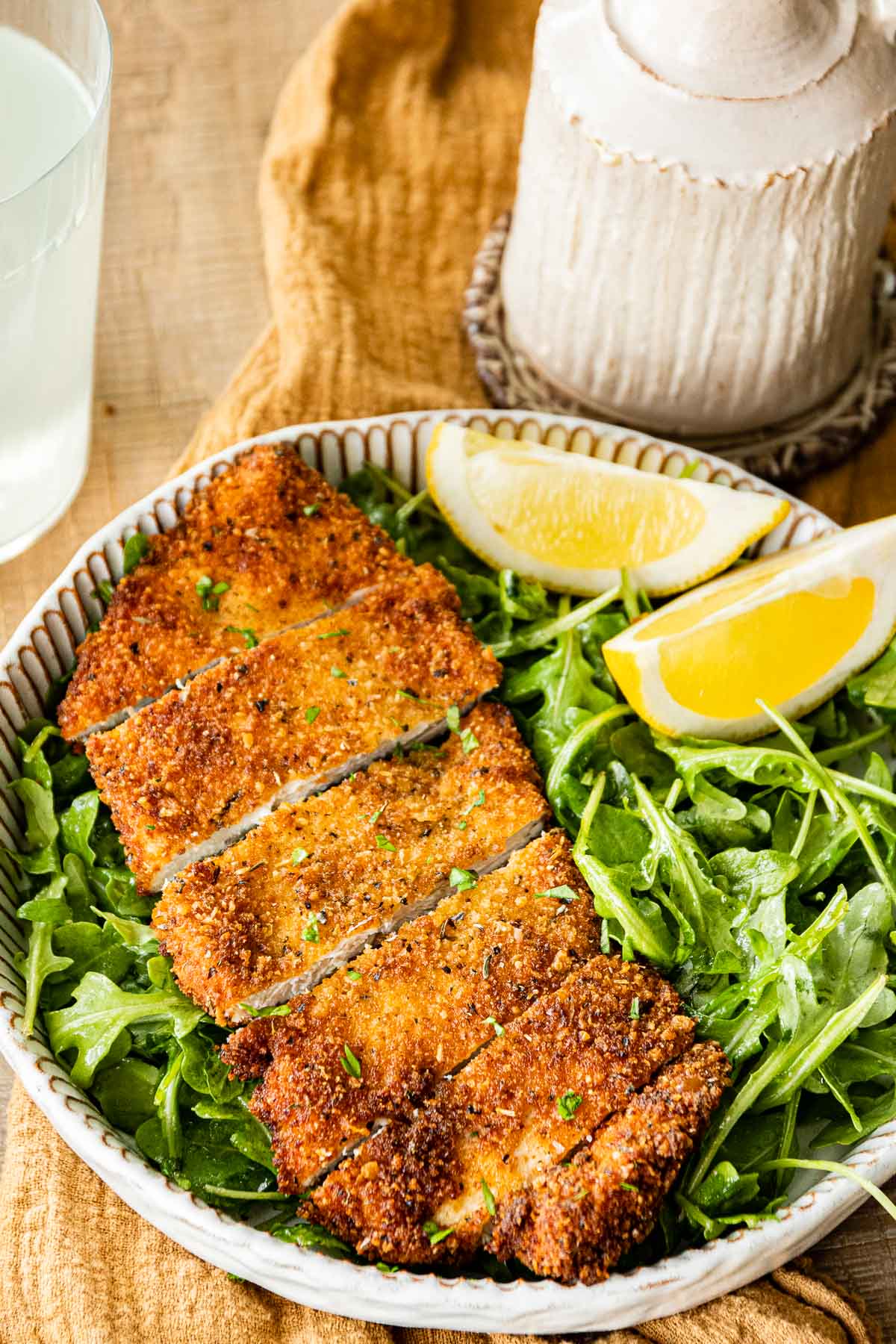 Crispy Breaded Chicken sliced on plate with greens and lemons