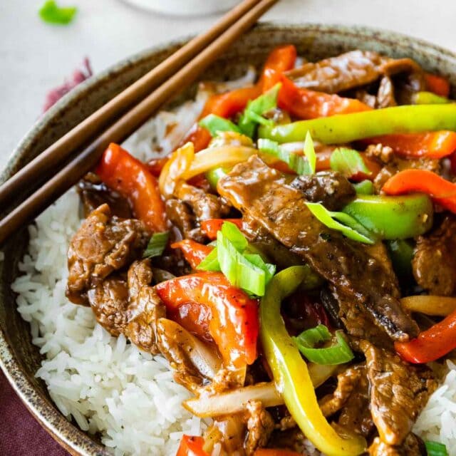 Easy Pepper Steak served over white rice in bowl with chopsticks