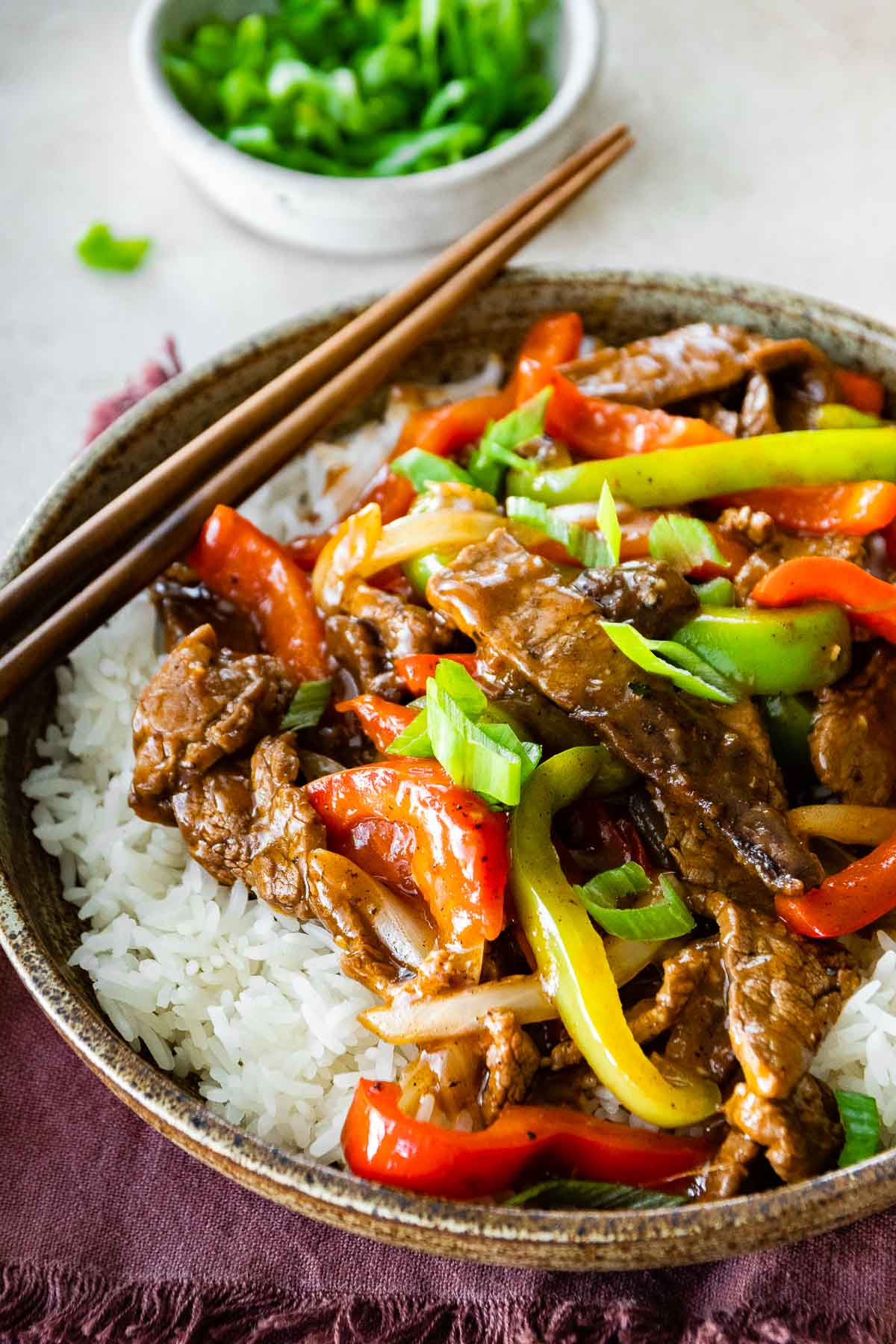 Easy Pepper Steak served over white rice in bowl with chopsticks