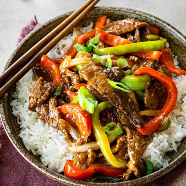 Easy Pepper Steak served over white rice in bowl with chopsticks