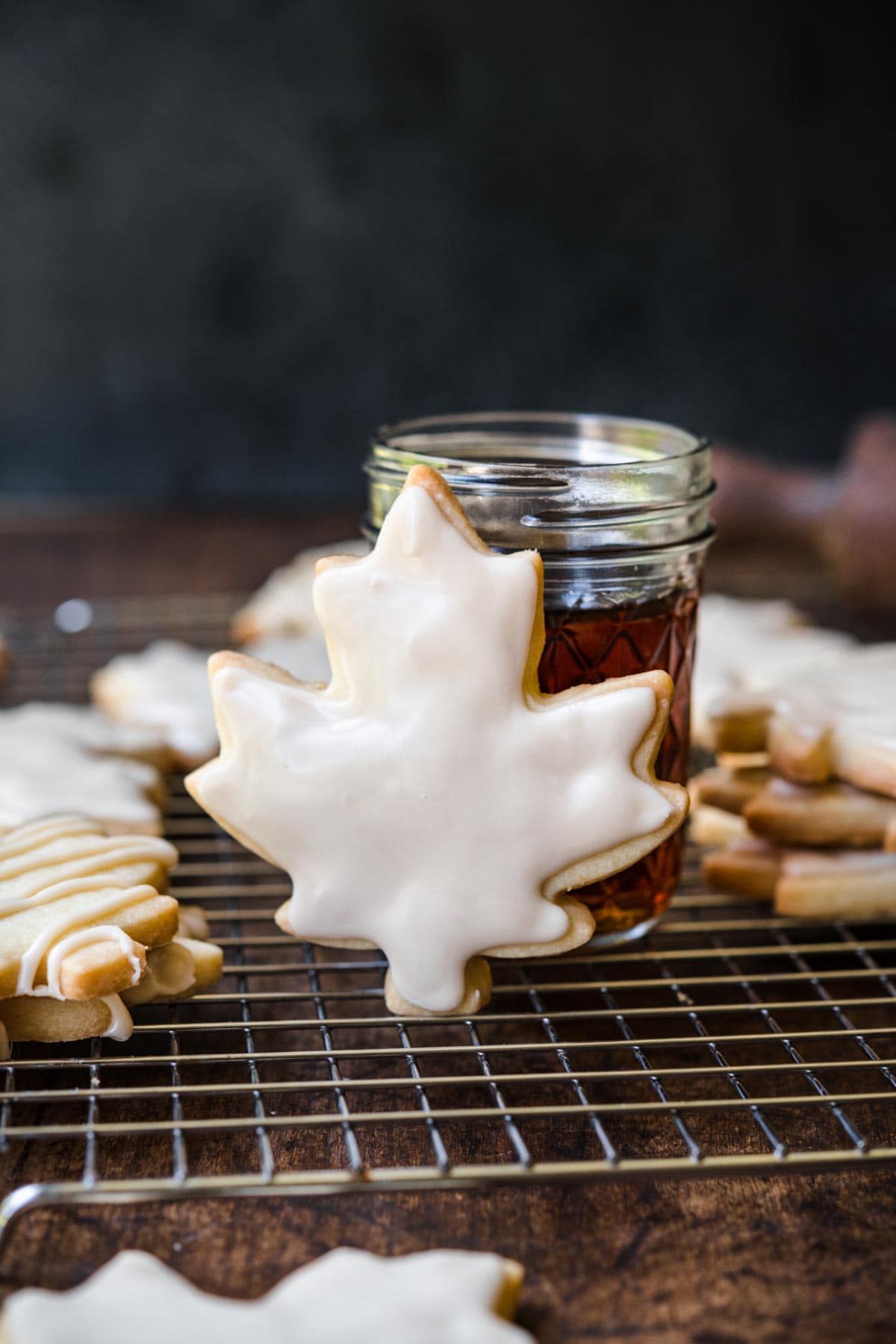 Glazed Maple Shortbread Cookies finished glazed cookies on cooling rack with jar of maple syrup