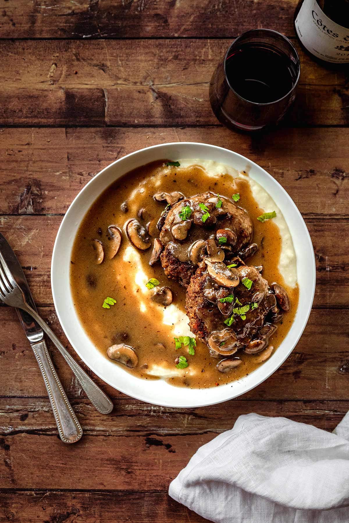 Hamburger Steaks with Mushroom Gravy served in a dish over mashed potatoes
