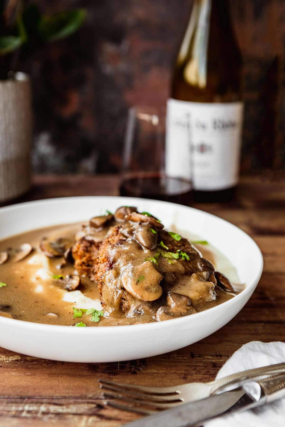 Hamburger Steaks with Mushroom Gravy served in a dish over mashed potatoes