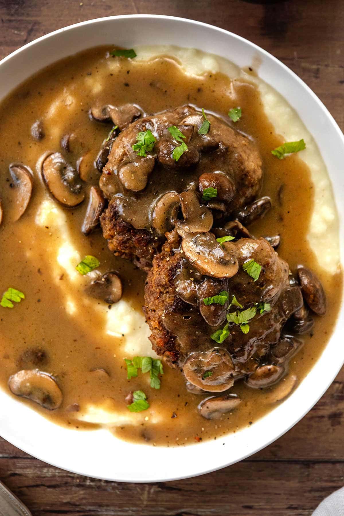 Hamburger Steaks with Mushroom Gravy served in a dish over mashed potatoes