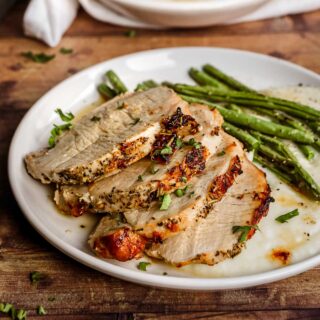 Herb Crusted Pork Loin sliced on plate with parsley garnish and green beans