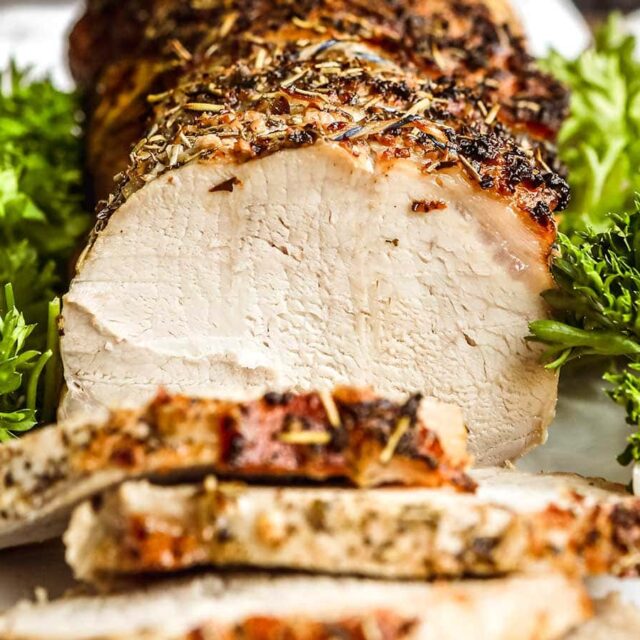 crusted meat sliced on plate garnished with greens