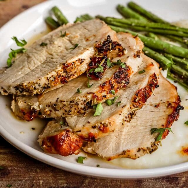 Pork Loin sliced on plate with parsley garnish and green beans