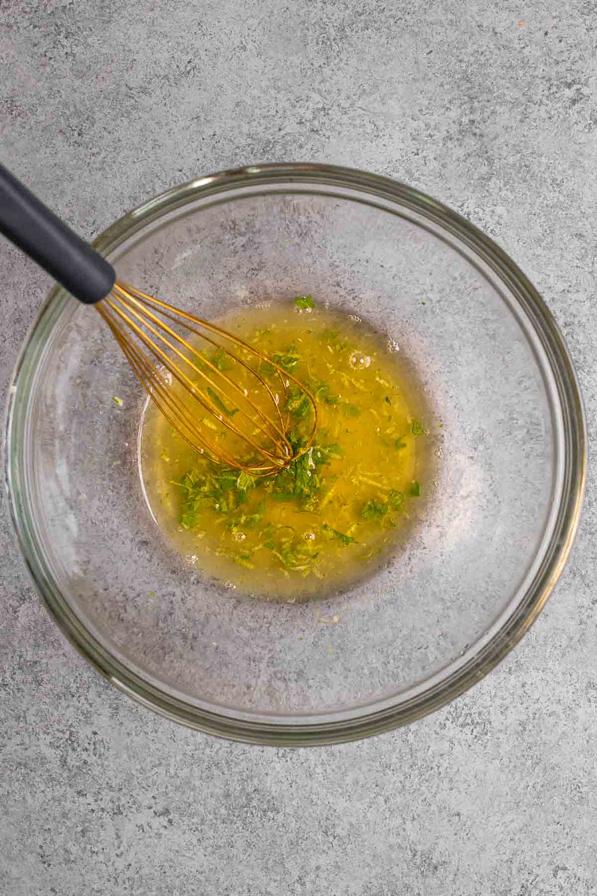 Dressing in mixing bowl with whisk for Honey Lime Berry Fruit Salad