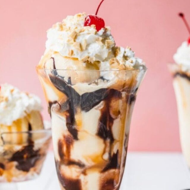 Sundaes in a sundae/milkshake glass with whipped cream and a cherry