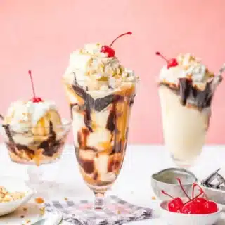 3 sundaes on a table with nuts and cerries
