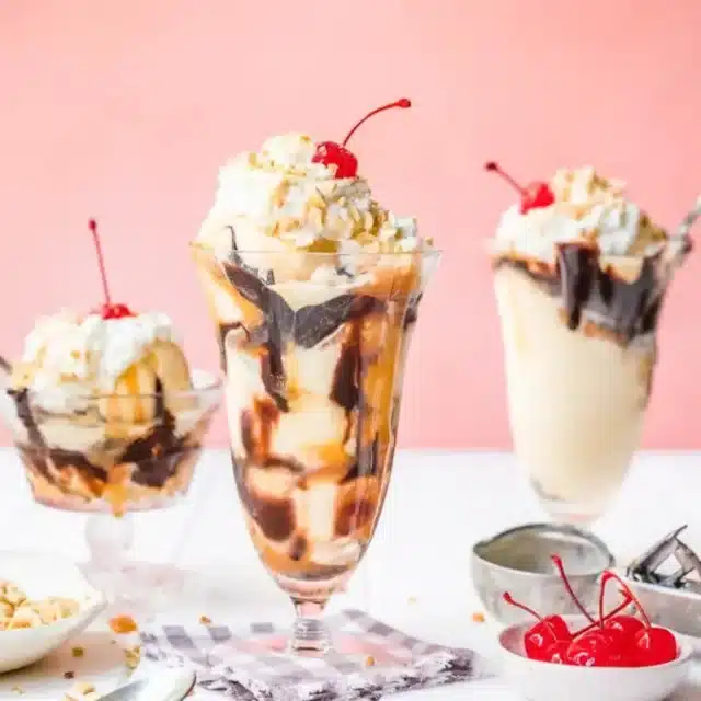 3 sundaes on a table with nuts and cerries