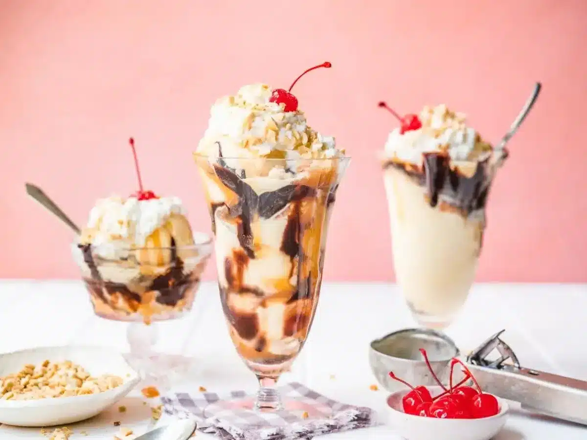 3 sundaes on a table with nuts and cerries 