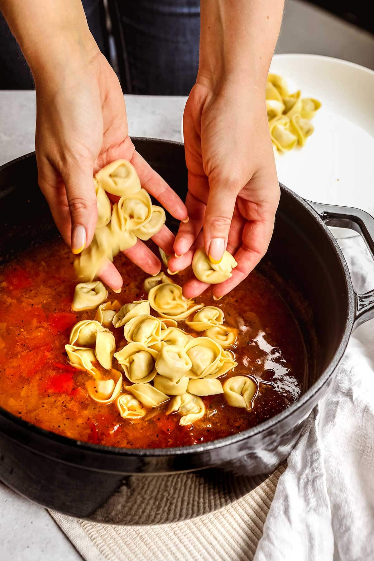 Italian Sausage Tortellini Soup in pot adding pasta