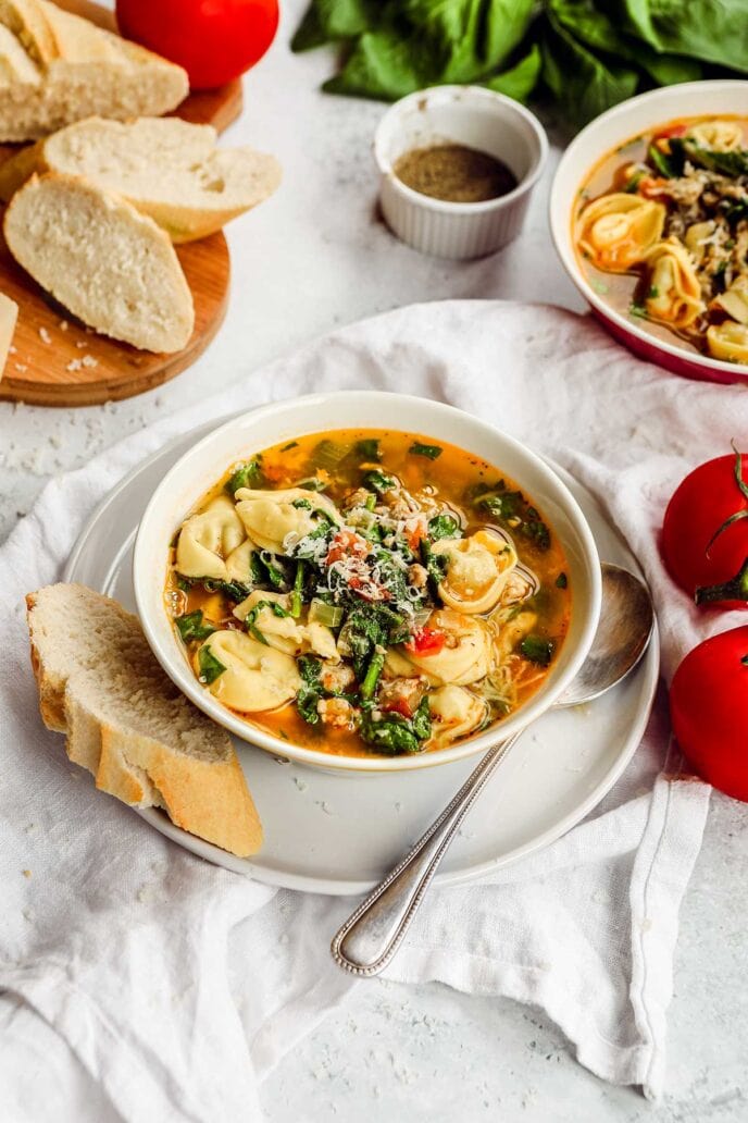 Italian Sausage Tortellini Soup in bowl with bread and spoon
