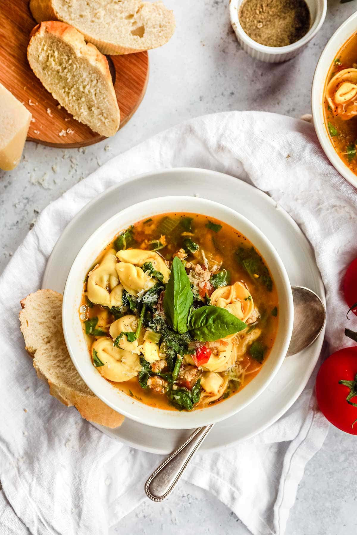 Italian Sausage Tortellini Soup in bowl with bread and spoon