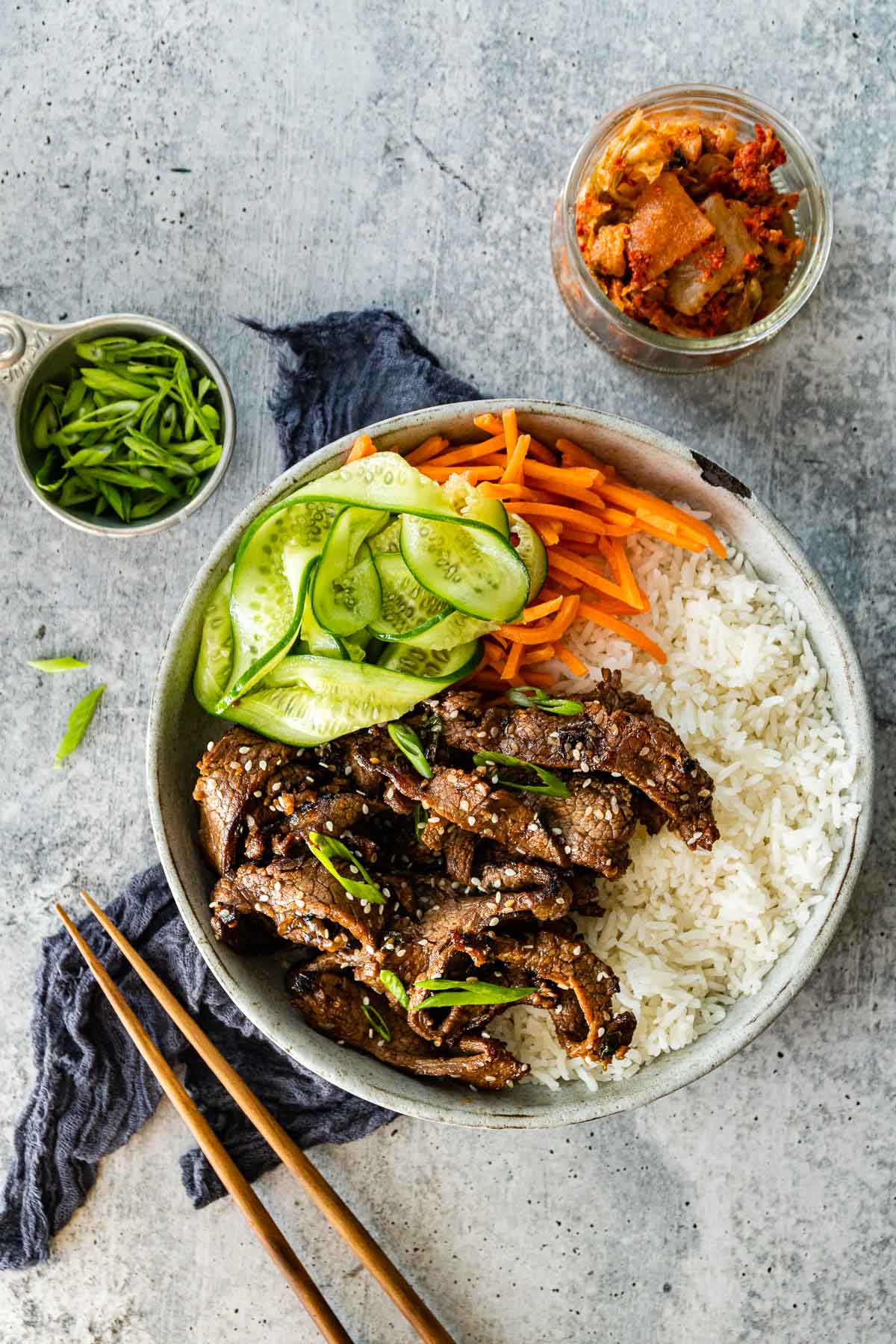 Korean Beef Bulgogi cooked beef slices in serving bowl with white rice, shredded carrots, and sliced cucumbers