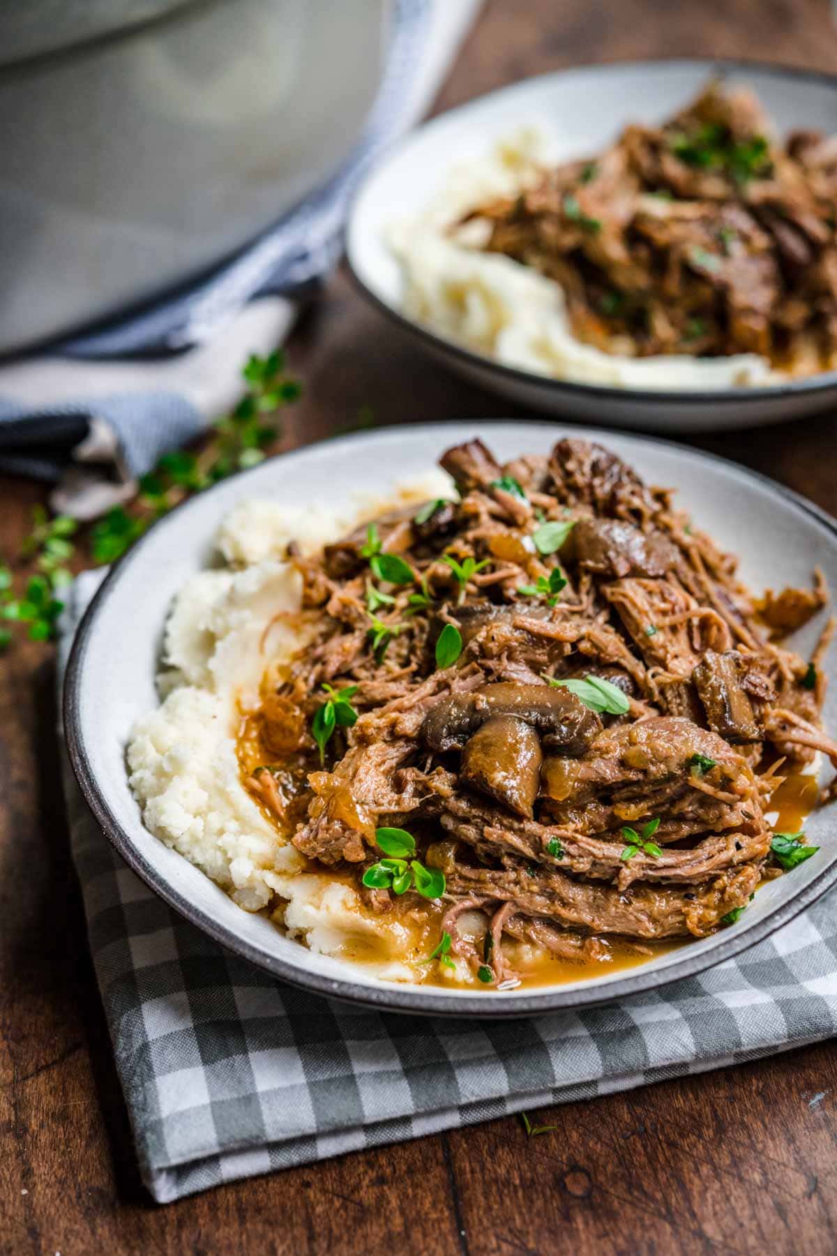 Mushroom Beef Roast shredded and garnished with fresh parsley served over mashed potatoes