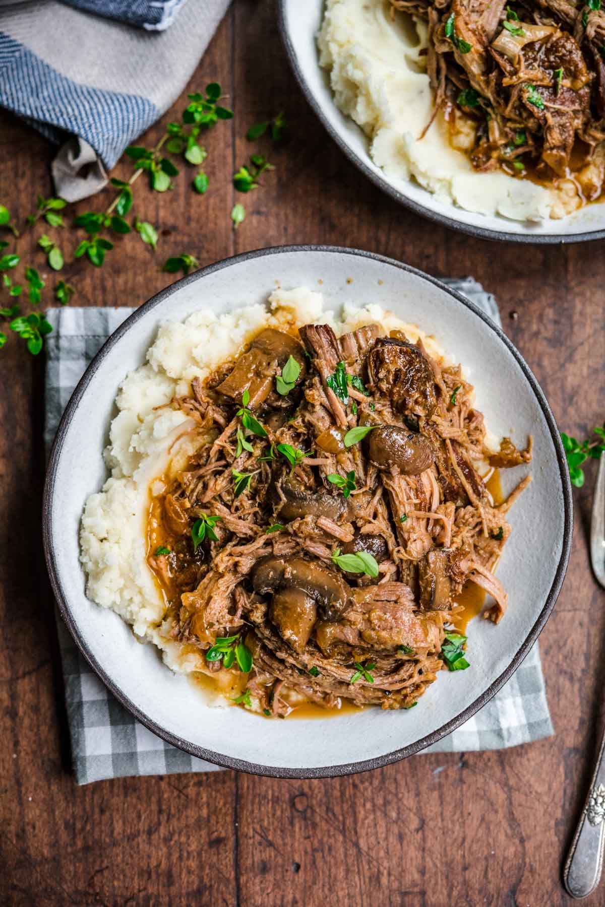 Mushroom Beef Roast shredded and garnished with fresh parsley served over mashed potatoes