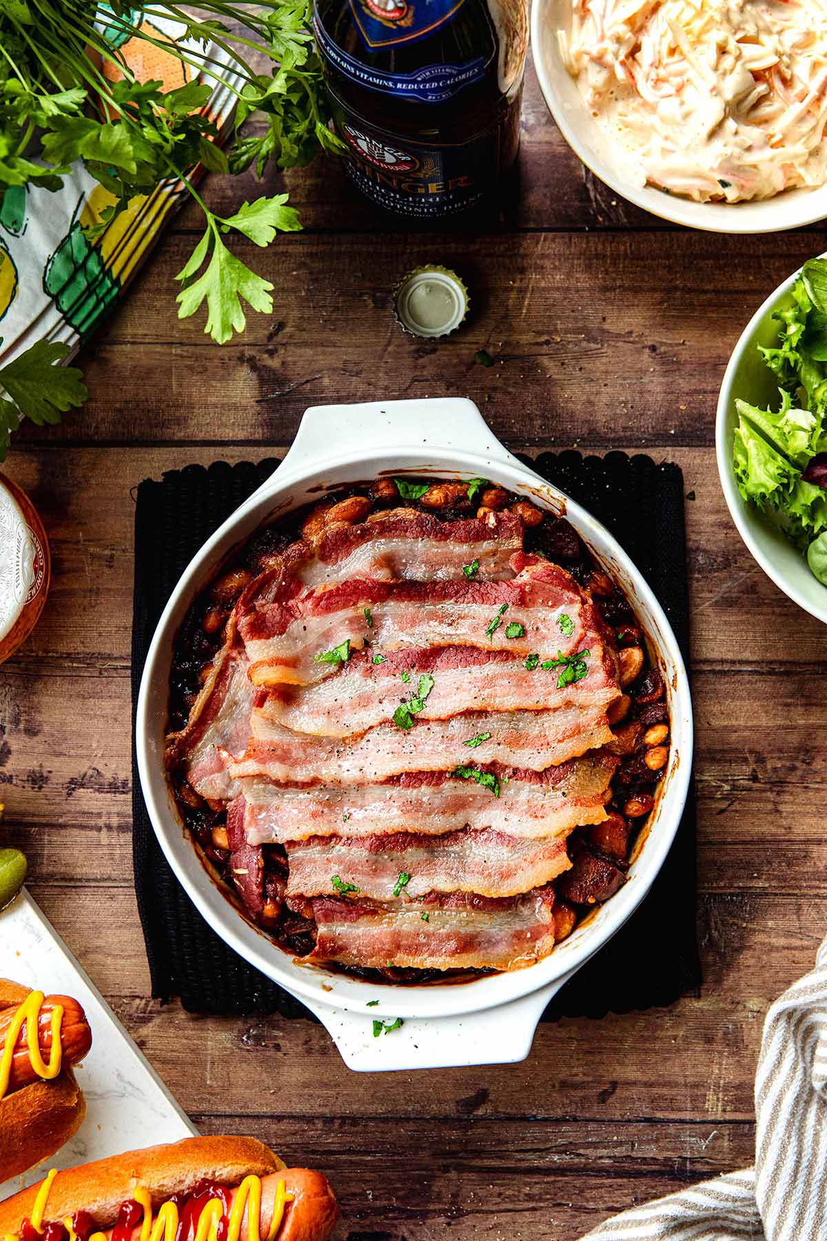 New England Baked Beans in baking dish wtih bacon slices layered on top