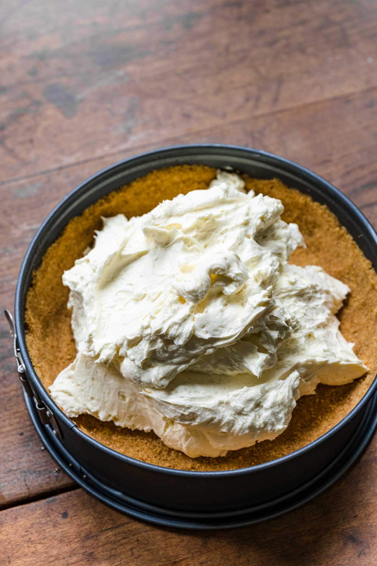 No-Bake Cheesecake filling mixture spreading onto crust in pan