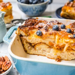 Orange Marmalade French Toast Bake in baking dish dusted with powdered sugar and garnished with pecans and fresh blueberries
