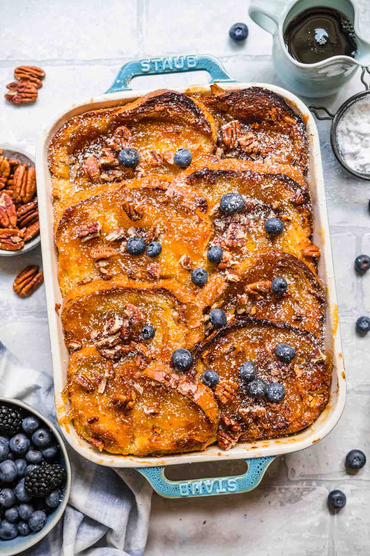 Orange Marmalade French Toast Bake in baking dish dusted with powdered sugar and garnished with pecans and fresh blueberries