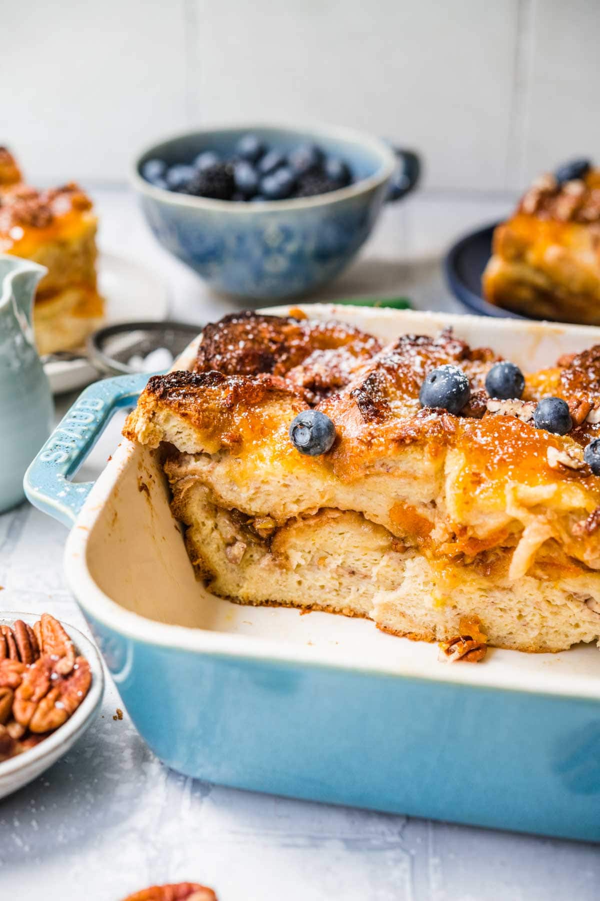 Orange Marmalade French Toast Bake in baking dish dusted with powdered sugar and garnished with pecans and fresh blueberries