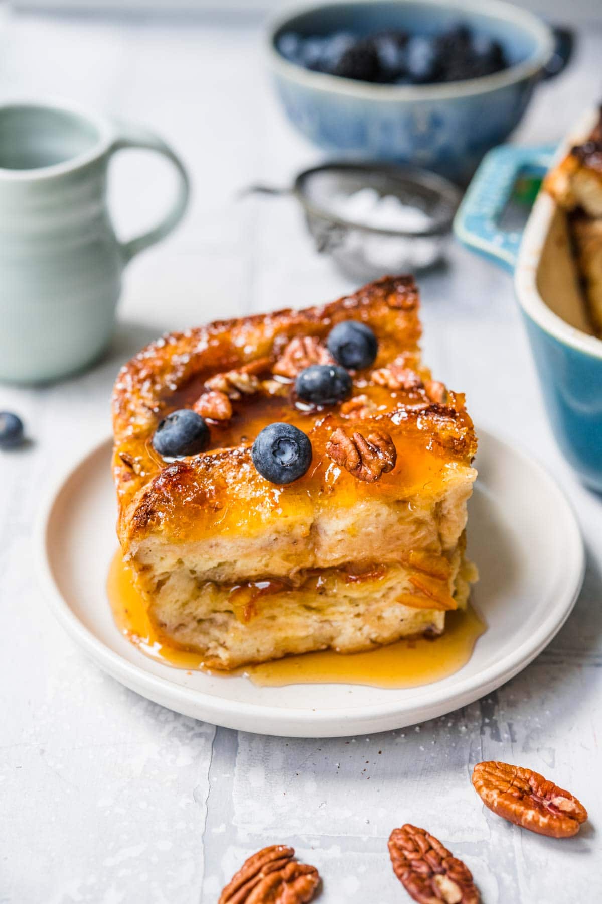 Orange Marmalade French Toast Bake slice on plate dusted with powdered sugar and garnished with pecans and fresh blueberries
