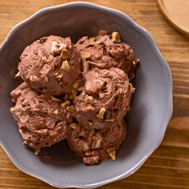 frozen chocolate ice cream scoops in a bowl with nuts and marshmallow