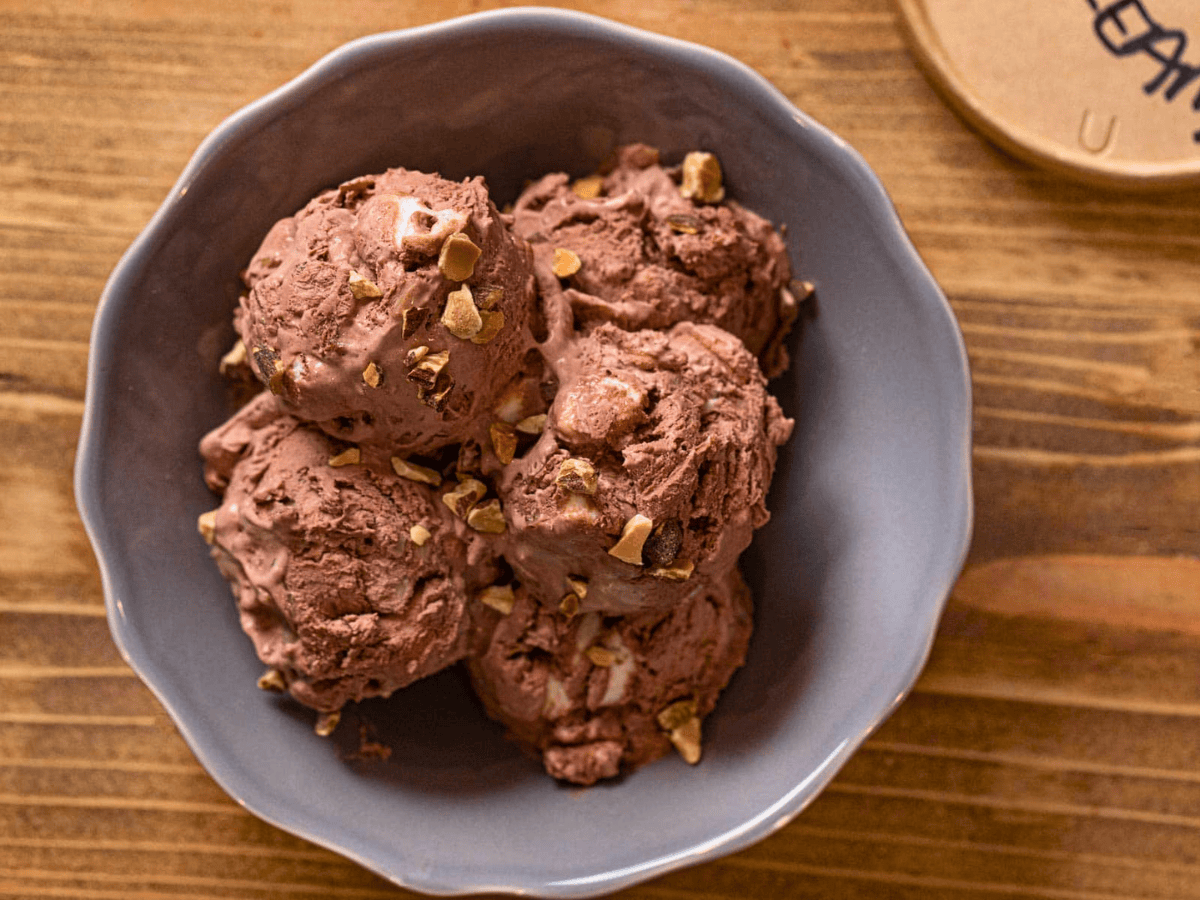 frozen chocolate ice cream scoops in a bowl with nuts and marshmallow