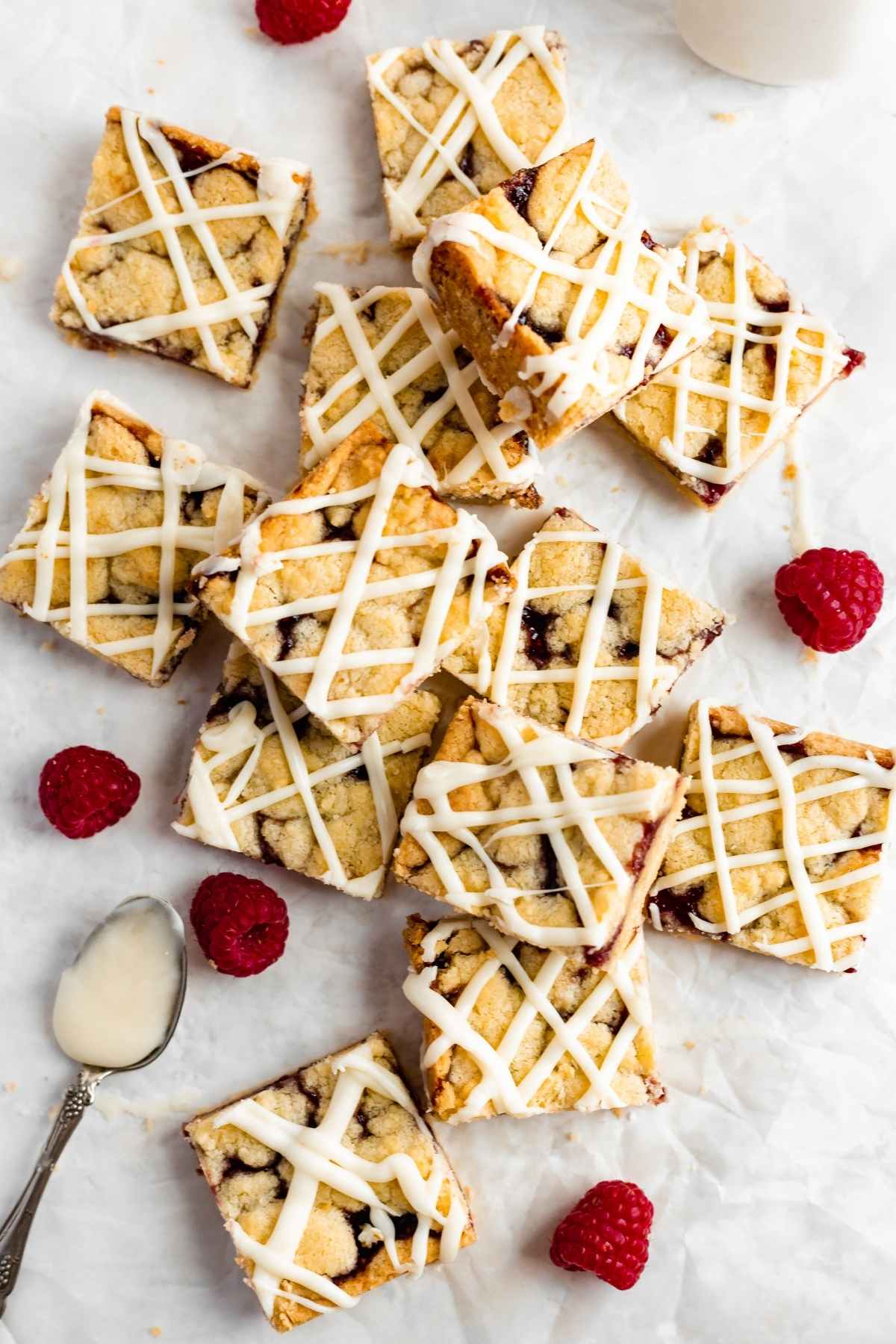 White Chocolate Raspberry Shortbread Bars sliced on parchment with fresh raspberry garnish