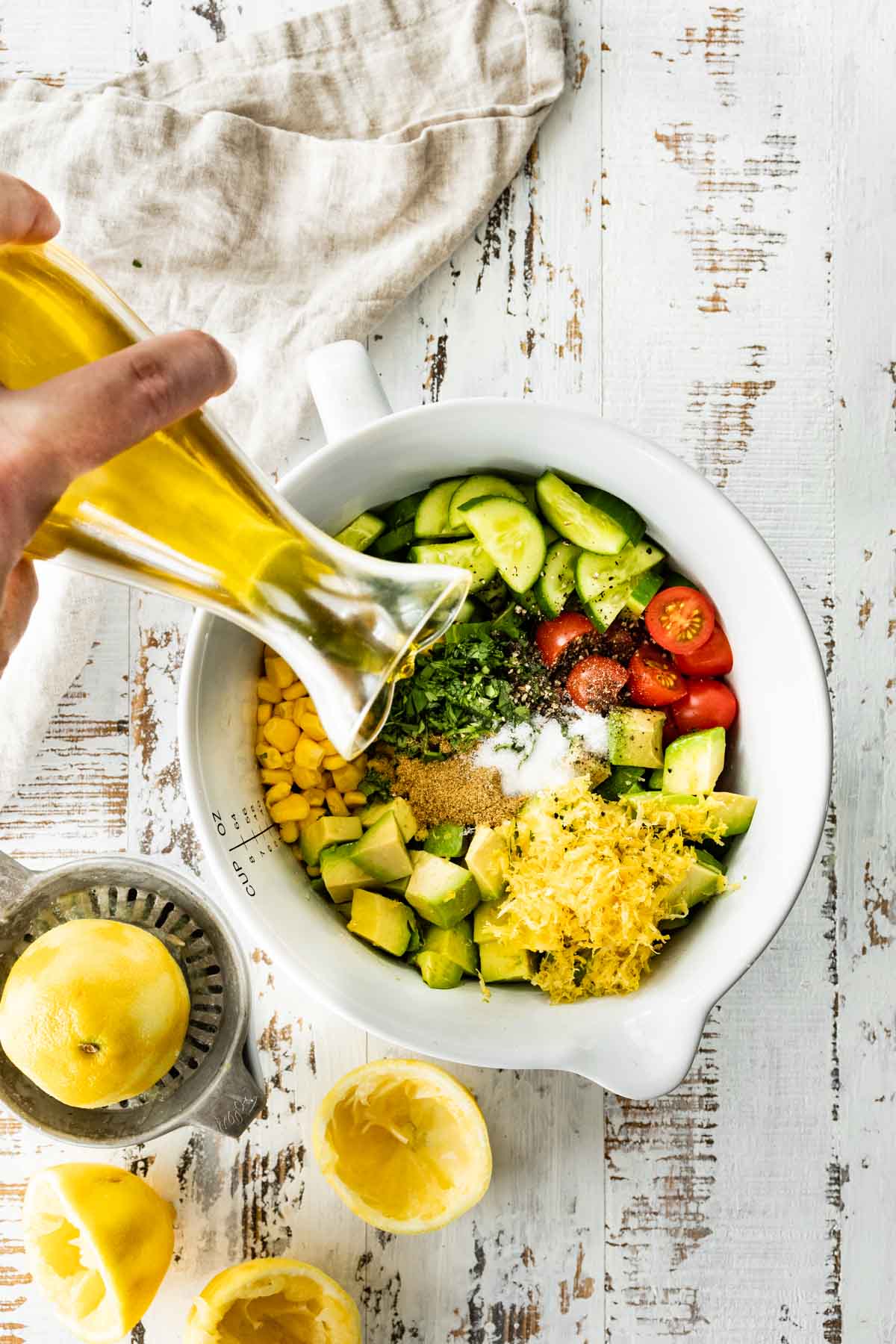 Ingredients for Avocado Tomato Corn Salad in mixing bowl with dressing being poured