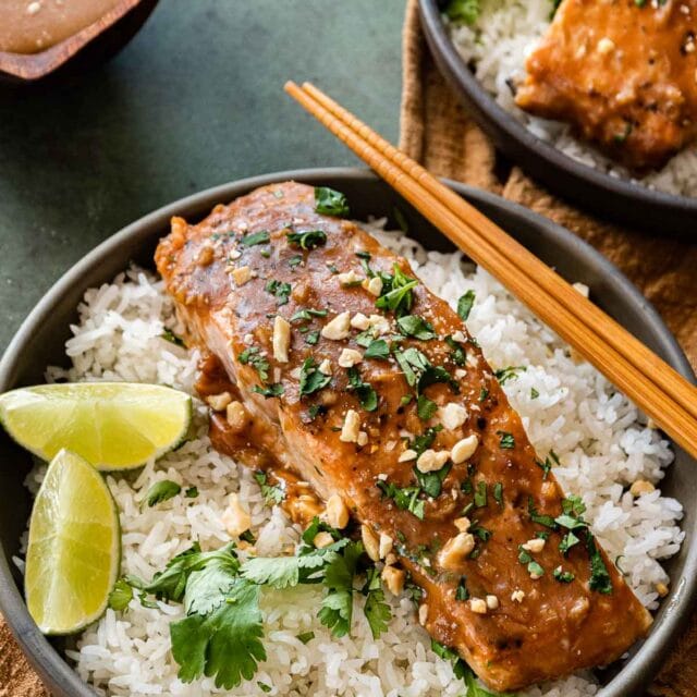 Baked Thai Peanut Salmon in serving bowl with rice and lime wedges