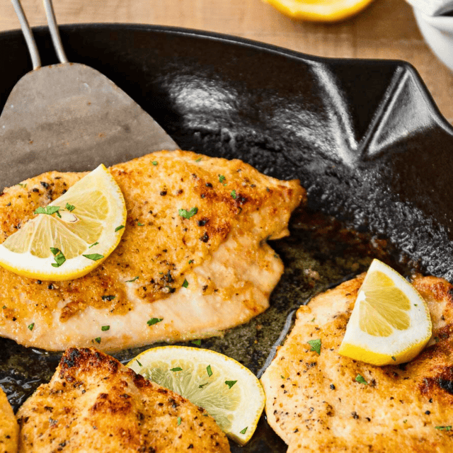 cooked poultry in cast iron with citrus slices on top with a spatula