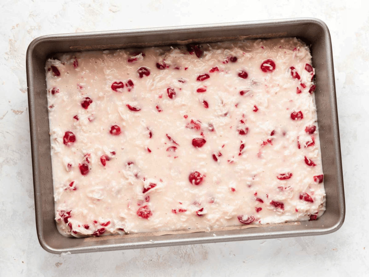 cherries mixed in cream on top of a bed of crust in a baking sheet