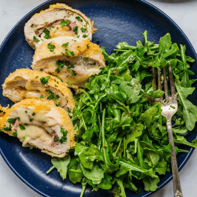 Plated stuffed chicken slices with arugula salad