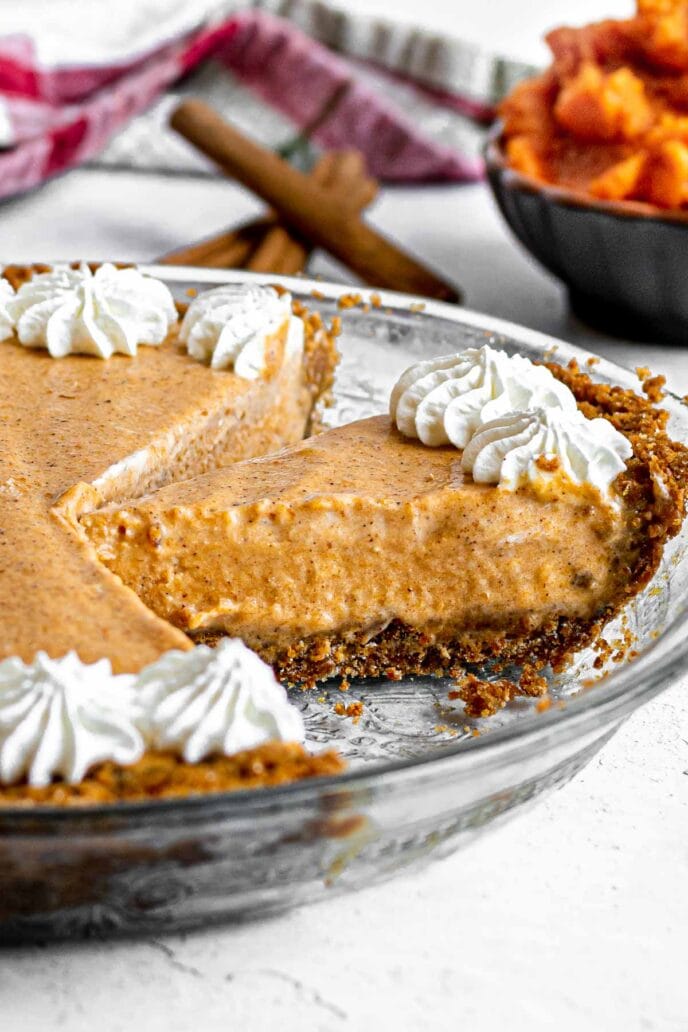 Frozen Pumpkin Ice Cream Pie with whip cream starts around crust edge, sliced in pie plate