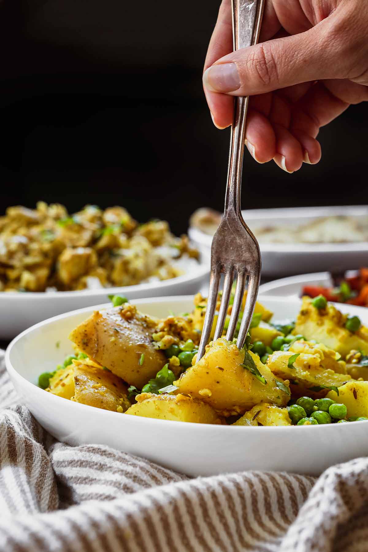 Indian Bombay Potatoes and Peas in serving bowl with fork