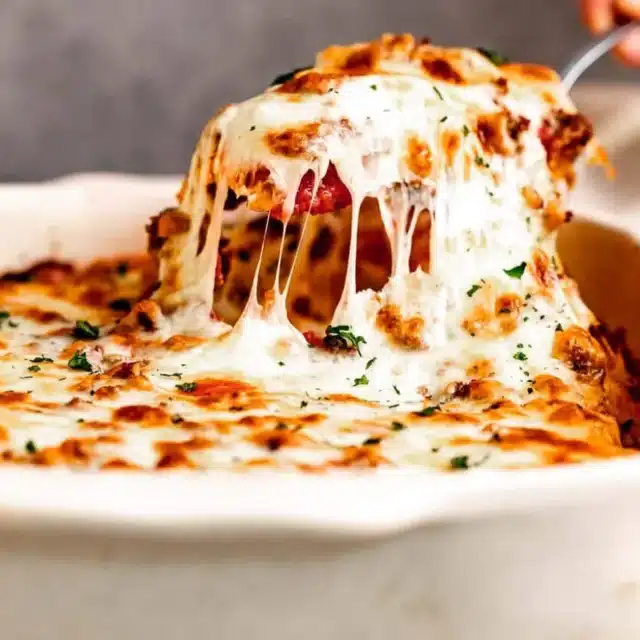 Cheesy dish being scooped out of pan