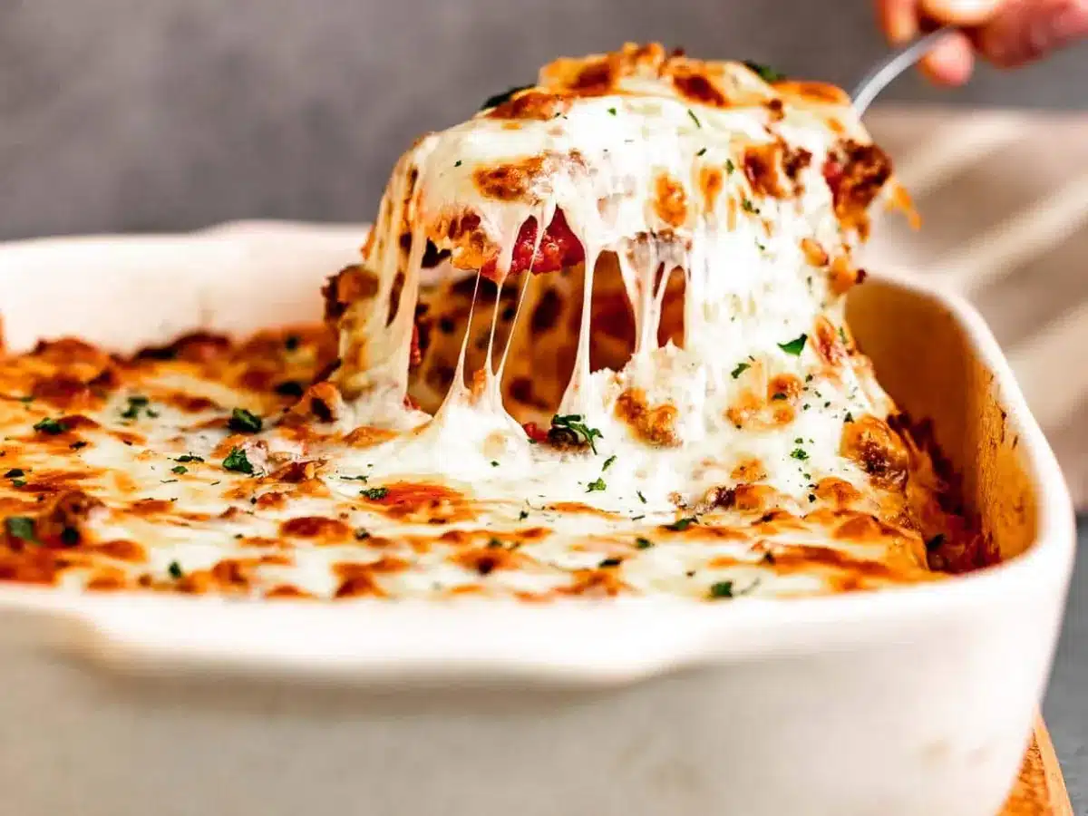 Cheesy dish being scooped out of pan