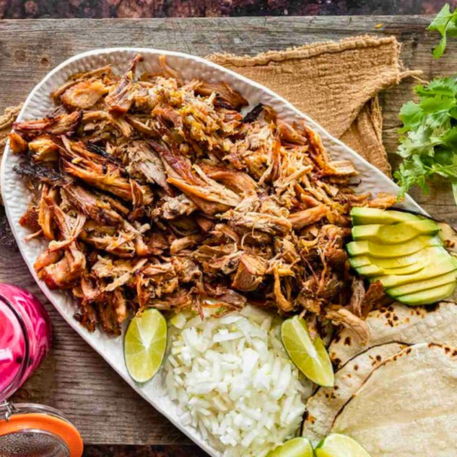 Platter of meat with rice, avocado, limes and tortillas