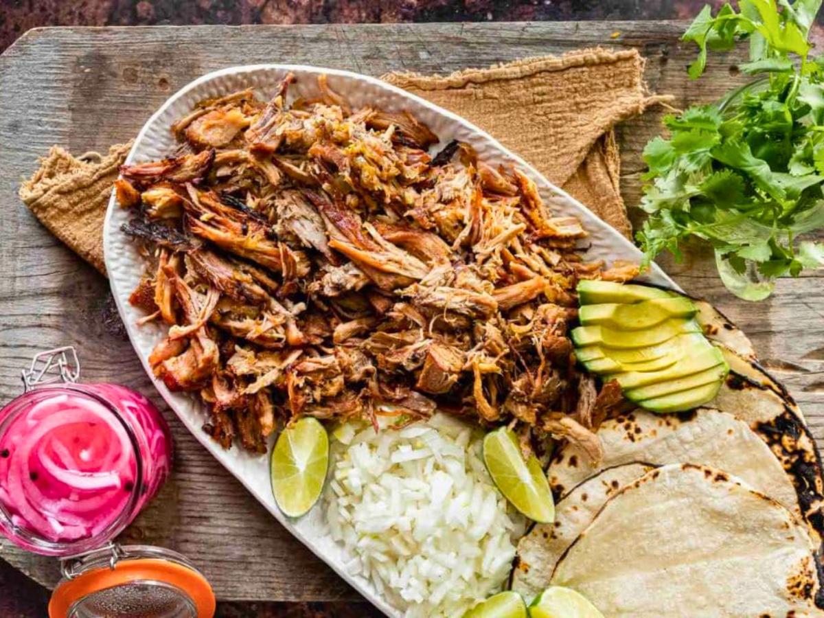 Platter of meat with rice, avocado, limes and tortillas